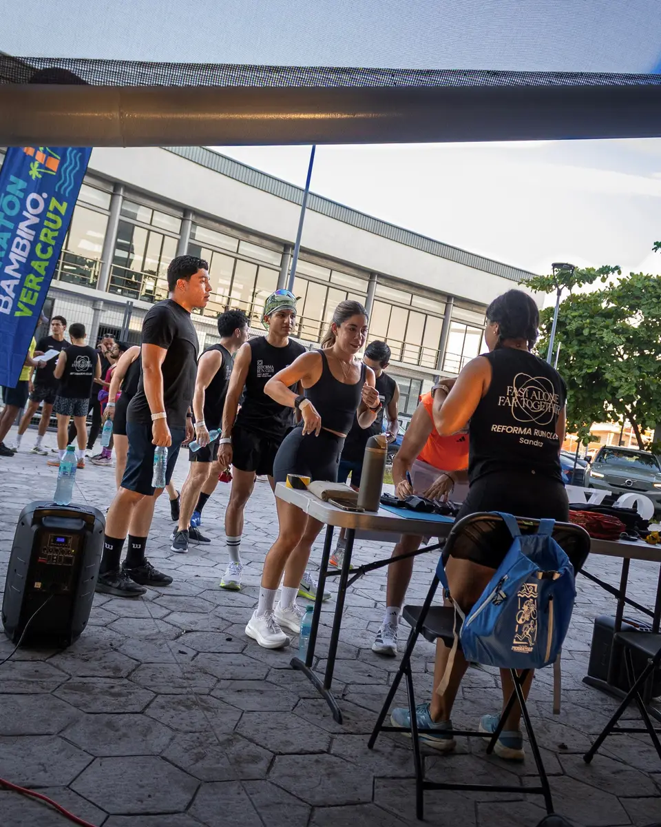 El grupo se reúne junto a la mesa de hidratación después del circuito, con una bocina y las mochilas en el suelo.