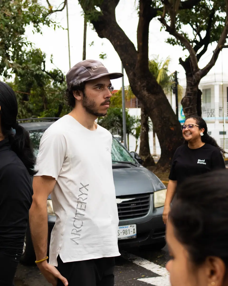 Dos corredores conversan junto a una camioneta antes de arrancar, uno con gorra y camiseta clara.